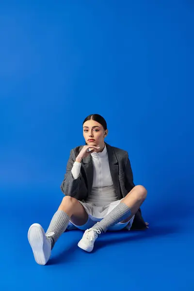 A stunning young woman sits on the floor, lost in thought with a hint of emotion on her face. — Stock Photo