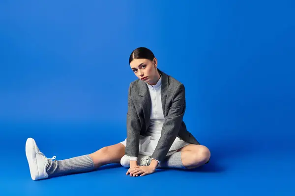Une belle jeune femme exprime ses émotions assise sur un fond bleu vif. — Stock Photo