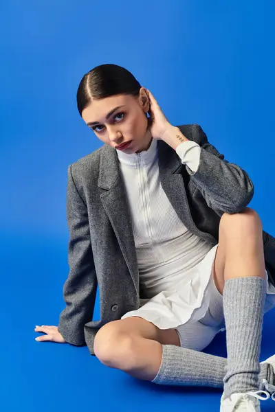 Stylish young woman showcases her emotions while seated on the floor, creating a captivating vibe. — Stock Photo
