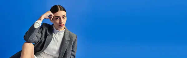A young woman in modern fashion shows deep emotion against a vivid blue background. — Stock Photo