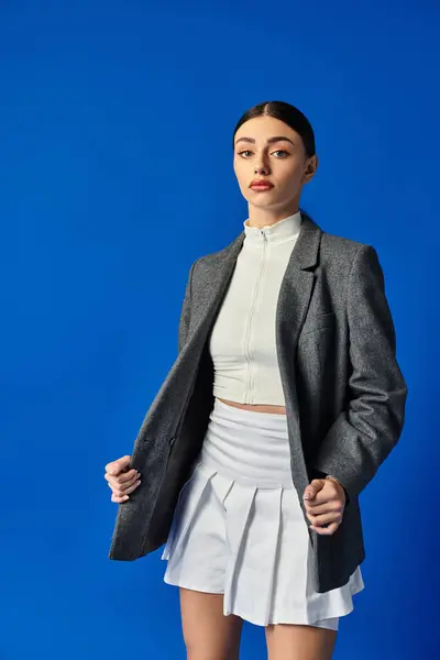 A young woman shows confidence in a chic outfit against a striking blue backdrop. — Stock Photo