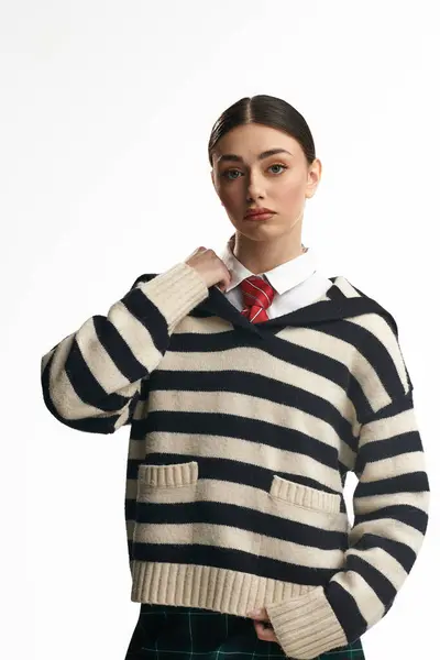 A young beautiful woman wearing a striped sweater looks thoughtfully with a serious expression. — Stock Photo