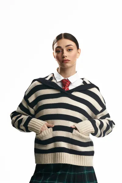 Young woman in soft light showcases emotions in a striped sweater and plaid skirt. — Stock Photo
