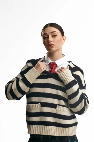 Young beautiful woman expresses emotion in stylish striped sweater with plaid tie in soft lighting. — Stock Photo
