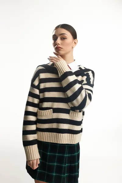 A young woman with a striking look showcases her emotions while posing in a vibrant striped sweater. — Stock Photo
