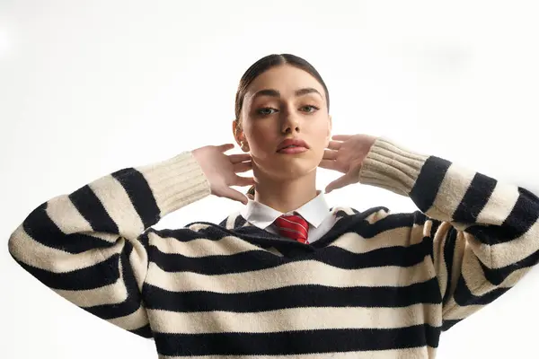 Young woman in a striped sweater and red tie poses gracefully, exuding elegance. — Stock Photo