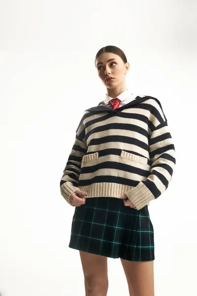 This emotional woman showcases a stylish outfit, combining a striped sweater and plaid skirt. — Stock Photo