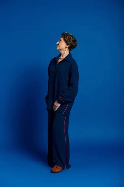 A stylish woman in her 60s poses gracefully, showcasing her timeless beauty in a trendy outfit. — Stock Photo