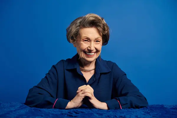 A beautiful woman in her 60s expresses confidence and charm while posing in trendy attire. — Stock Photo