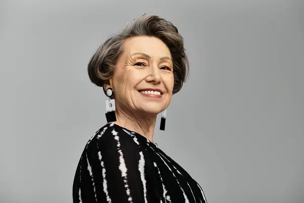 A stylish woman in her 60s poses confidently, showcasing her elegant attire and timeless beauty. — Stock Photo