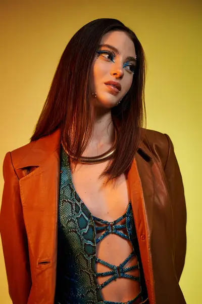 A confident young woman showcases her snake print outfit and bold makeup against a bright backdrop. — Stock Photo