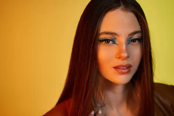 Mujer joven muestra maquillaje vibrante bajo luces de estudio. - foto de stock