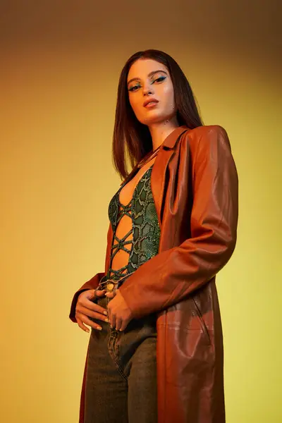 A young woman poses confidently in trendy snake print attire and striking makeup, exuding style. — Stock Photo