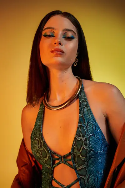 A beautiful young woman poses confidently in snake print attire with striking makeup. — Stock Photo