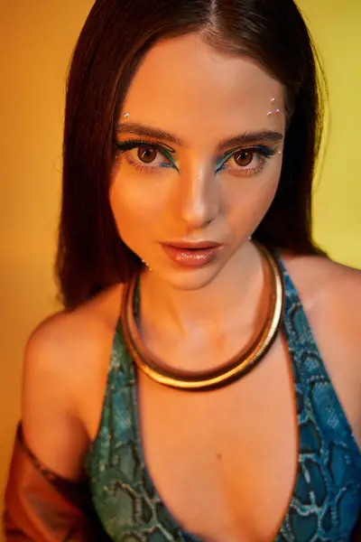 A confident young woman flaunts snake print fashion, bold makeup, and a striking necklace. — Stock Photo