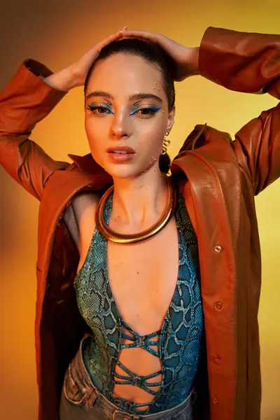 A young woman showcases stunning makeup and stylish snake print attire in a creative atmosphere. — Stock Photo