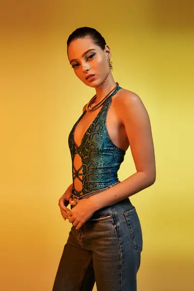 Una joven de moda exhibe su atrevido atuendo de serpientes y su impresionante maquillaje en un estudio. - foto de stock
