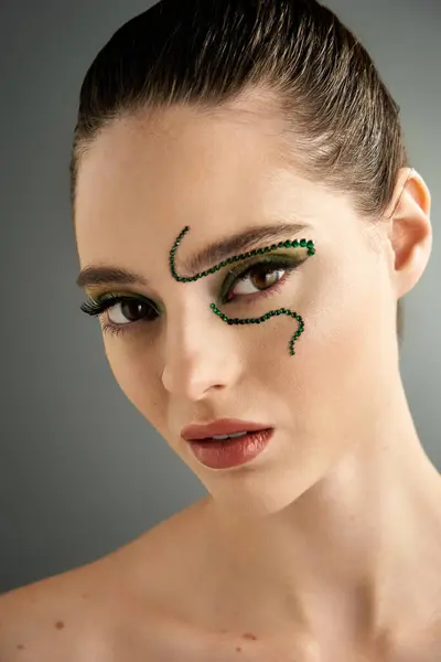 A stunning young model showcases intricate snake makeup artistry in a stylish studio environment. — Stock Photo