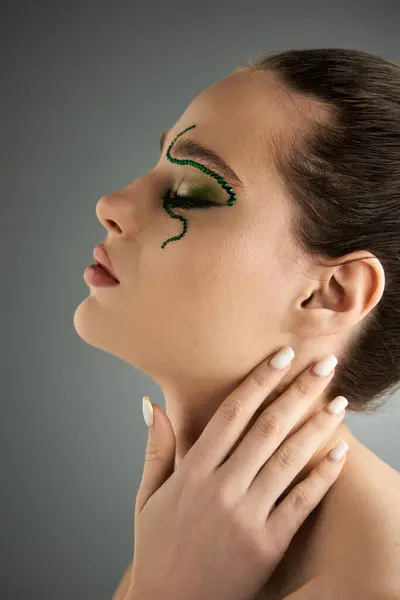 A beautiful young woman showcases striking snake-inspired makeup against a modern backdrop. — Stock Photo