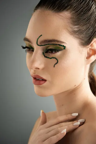 Mujer joven con maquillaje intrincado inspirado en serpientes posa elegantemente en un estudio moderno. — Stock Photo