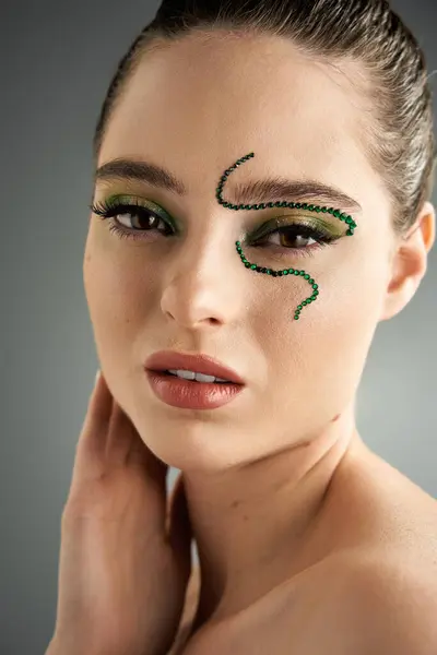 A beautiful young woman poses in a studio, showcasing impressive snake-themed makeup artistry. — Stock Photo