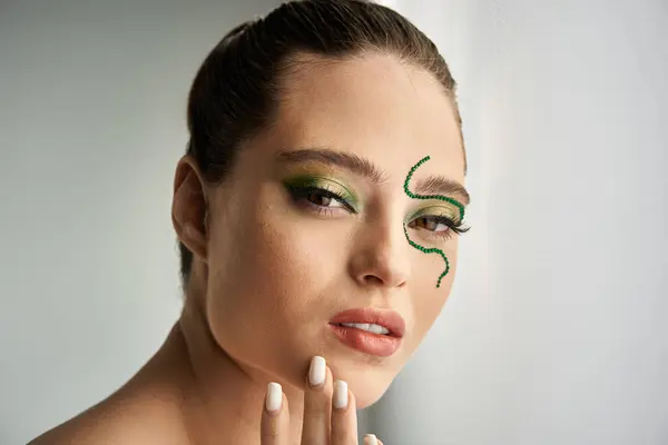 A beautiful young woman showcases captivating snake-inspired makeup while posing in a studio. — Stock Photo
