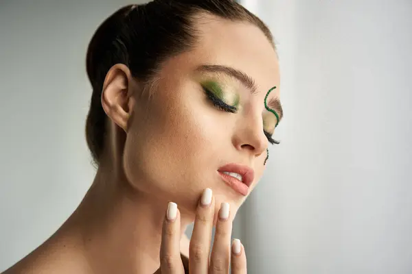 A beautiful young woman poses elegantly in a studio, showcasing mesmerizing snake makeup artistry. — Stock Photo