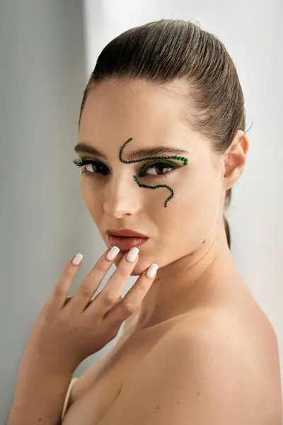 Young woman showcases intricate snake makeup, blending artistry and beauty in a creative studio. — Stock Photo