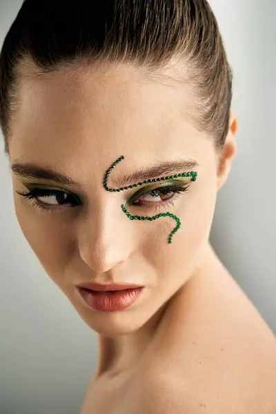 A beautiful young woman showcases intricate snake-themed makeup artistry in a studio. — Stock Photo