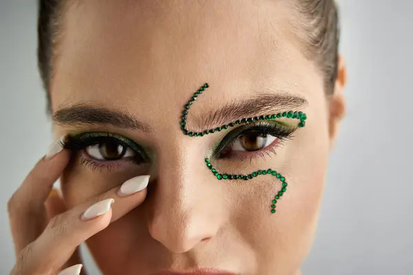 A stunning young woman poses with intricate snake makeup in a contemporary studio environment. — Stock Photo