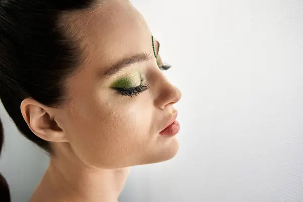 Beautiful young woman poses gracefully in studio with captivating snake-themed makeup artistry. — Stock Photo