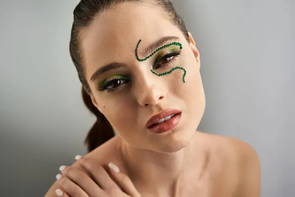 A beautiful young woman showcases captivating snake makeup in a modern studio environment. — Stock Photo