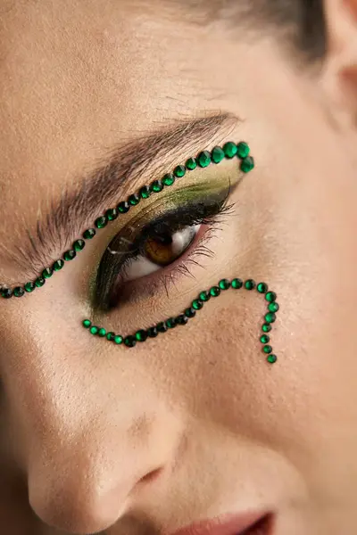 A beautiful young woman showcases mesmerizing snake makeup art while posing in a studio. — Stock Photo