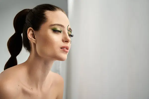 A beautiful young woman showcases captivating snake makeup in an artistic studio environment. — Stock Photo