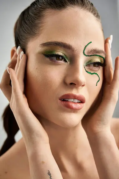 A beautiful young woman showcases intricate snake makeup in a studio, radiating beauty and trend. — Stock Photo