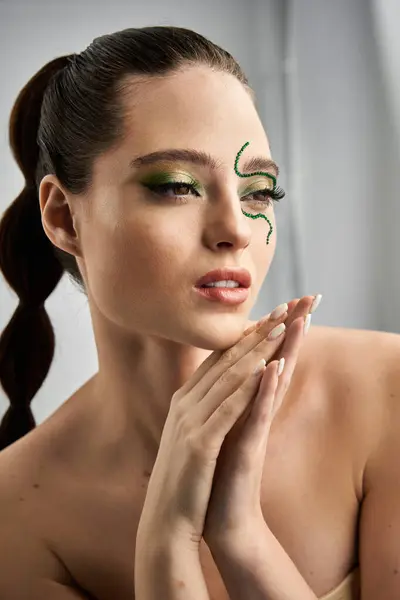 A beautiful young woman poses gracefully in a studio, featuring striking snake-inspired makeup. — Stock Photo