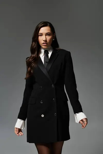A beautiful young woman showcases her fashionable outfit while posing elegantly in the studio. — Stock Photo