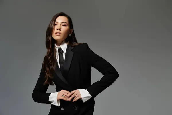 A beautiful young woman showcases her stylish attire while striking a confident pose in a studio. — Stock Photo