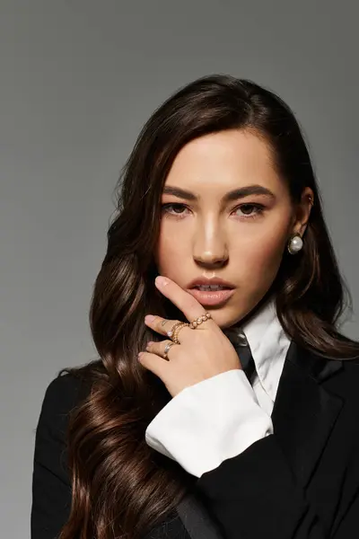 Una bella giovane donna con lunghi capelli castani posa con grazia, trasudando fiducia in un abbigliamento elegante. — Foto stock