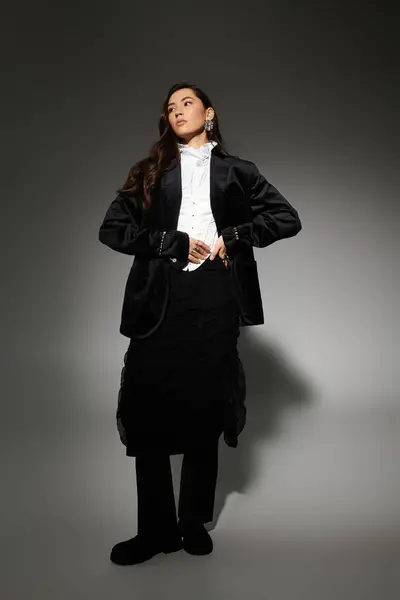 Young woman with shiny brown hair poses elegantly in a stylish outfit in the studio. — Stock Photo