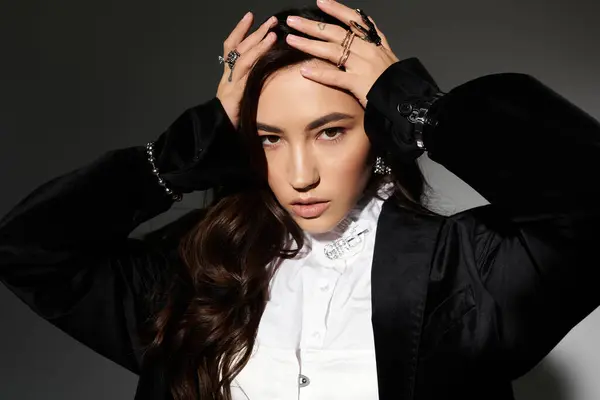 A young woman exudes confidence with shiny brown hair and an elegant outfit in a sleek studio. — Stock Photo