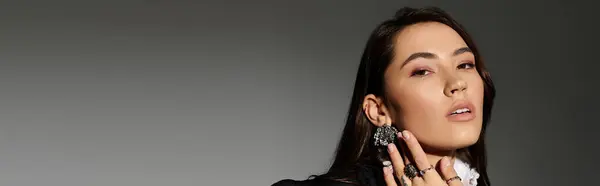 A young woman with shiny brown hair poses elegantly in a stylish outfit against a grey backdrop, banner — Stock Photo