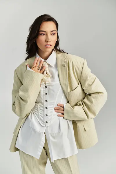 A young woman poses confidently in a chic outfit against a neutral backdrop. — Stock Photo