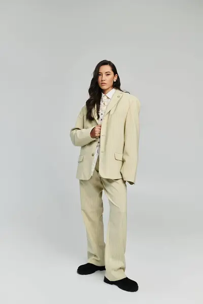 A stylish young woman in a chic oversized suit embodies modern fashion in a minimalist studio. — Stock Photo