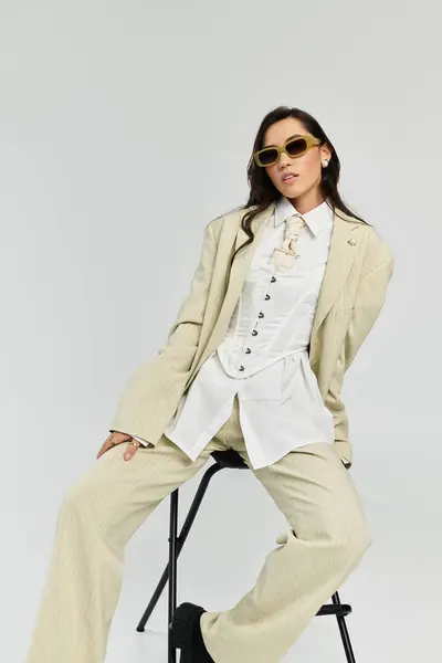 Elegant woman in a chic outfit confidently poses against a plain backdrop, exuding style and grace. — Stock Photo