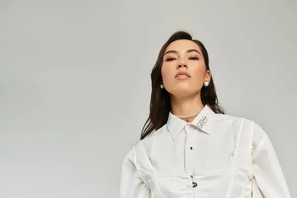 Une jeune femme rayonnante modèle la mode contemporaine dans une pose élégante sur un fond minimaliste. — Photo de stock