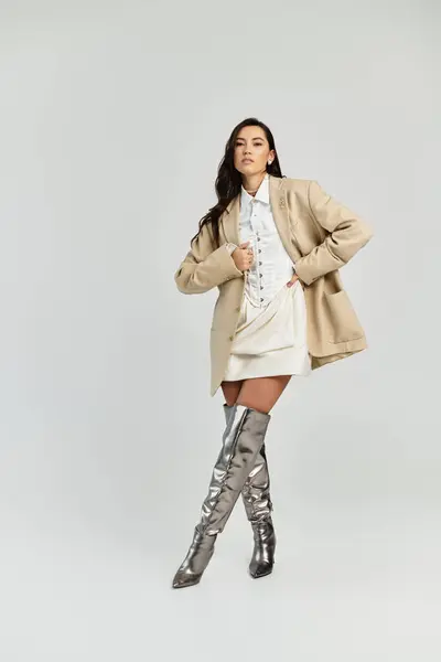 Confident young woman stands elegantly, showcasing a chic look with metallic knee high boots. — Stock Photo
