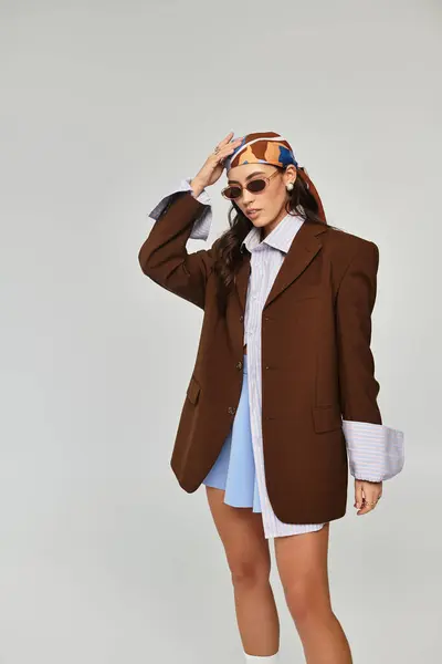 A young woman poses confidently in a trendy outfit against a simple backdrop. — Stock Photo