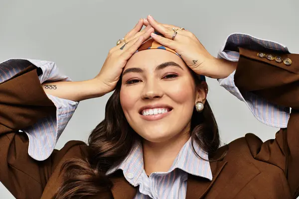 A beautiful and trendy woman poses playfully with hands on her head, showcasing her chic style. — Stock Photo