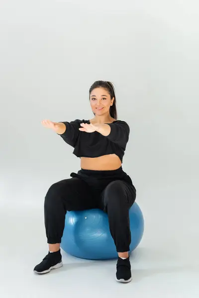 A fit woman engages in a dynamic workout session using a stability ball for strength training. — Stock Photo
